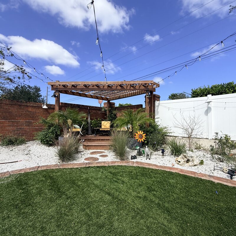 Custom wood pergola with string lighting, seating and a landscaped backyard