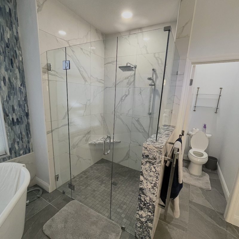 Bathroom remodel with marble-look shower tile, a glass enclosure and built-in bench